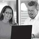 Two DCLI employees looking at laptop in office
