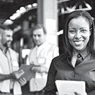 Business woman smiling standing in front of two male workers looking at a clipboard